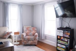 a living room with a chair and a flat screen tv at Cityside Escape Spacious with Game Room & Fire Pit in Geneva +32 photos