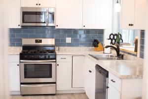 a kitchen with white cabinets and a stove and a sink at Cityside Escape Spacious with Game Room & Fire Pit in Geneva