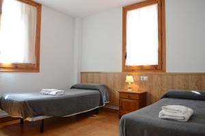 a room with two beds and a table and two windows at Habitacions La Coma de Taüll in Taull +13 photos