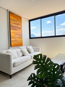 a living room with a white couch and large windows at Apartamento novo - garagem inclusa in Palmas