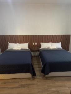 two beds sitting next to each other in a room at Hotel Mochomos Huajuapan in Huajuapan de León