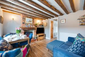 ein Wohnzimmer mit Tisch und Stühlen und einem Kamin in der Unterkunft Puddingmoor Cottage in Beccles