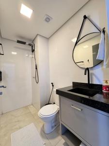 a bathroom with a toilet and a sink and a mirror at Apartamento novo - garagem inclusa in Palmas