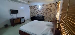 Un dormitorio con una cama y una silla y un televisor. en Skyfield Hotel & Suits, en Lekki