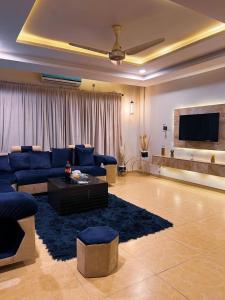 a living room with blue couches and a flat screen tv at OSMA Living Full Furnished Apartment In Islamabad in Rawalpindi