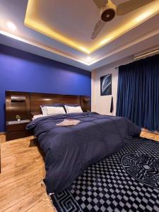 a bedroom with a large bed with a blue wall at OSMA Living Full Furnished Apartment In Islamabad in Rawalpindi