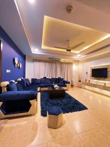 a large living room with blue couches and a tv at OSMA Living Full Furnished Apartment In Islamabad in Rawalpindi