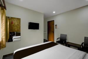 a bedroom with a bed and a tv on the wall at Hotel O The Pramaan in Kukatpalli