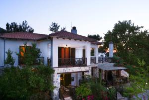 une maison blanche avec un balcon et des arbres dans l'établissement Menir Luxury Apartments, à Prinos