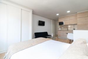Un dormitorio con una cama blanca y una cocina. en Estudio Vigo by Plaza España, en Vigo