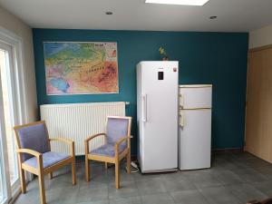 a room with a refrigerator and two chairs and a map at De Zandhoorn in De Panne