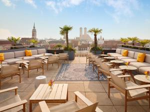 eine Terrasse mit Tischen und Sofas auf einem Dach in der Unterkunft Mandarin Oriental, Munich in München