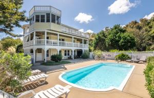 an exterior view of a house with a pool and chairs at Show Boat in Kitty Hawk