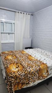 Un dormitorio con una manta de guepardo en una cama en Casa de Férias, en Capão da Canoa 7 fotos más