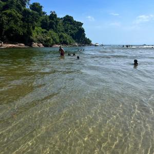 un groupe de personnes dans l'eau sur une plage dans l'établissement Kitnet Boraceia mar e sol, à Bertioga