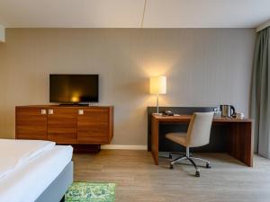 a hotel room with a bed and a desk with a television at Mercure Stuttgart Sindelfingen an der Messe in Sindelfingen