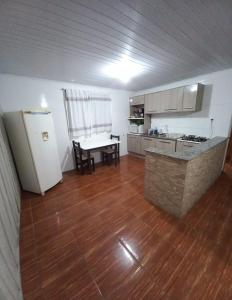 an empty kitchen with a table and a refrigerator at Casa de Hóspedes Espaçosa - Auto Check-In - Mafra SC in Mafra