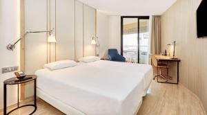een slaapkamer met een groot wit bed en een bureau bij NH Imperial Playa in Las Palmas de Gran Canaria +54 foto's