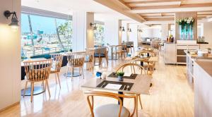 a restaurant with tables and chairs and a view of a harbor at NH Imperial Playa in Las Palmas de Gran Canaria