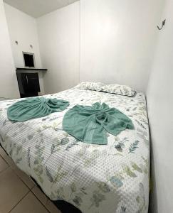 マナウスにあるQuarto no centroの寝室に緑色の服が置かれたベッド