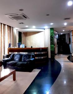a living room with a black leather couch at Hotel Presidente Asunción in Asunción