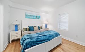 een witte slaapkamer met een bed met een blauwe deken bij Laketown Wharf 1134 in Panama City Beach +24 foto's