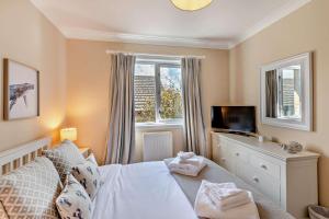 a bedroom with a bed and a tv and a window at Budle View - Belford in Belford