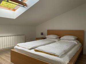 a bedroom with a bed with white sheets and a window at All Seasons Apartments Laško in Laško