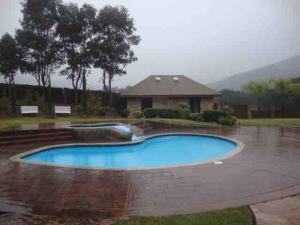 a swimming pool in the rain in front of a house at Baja Vineyard Lodge - Luxury in Valle de Guadalupe with pool in Ensenada