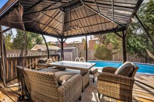 a patio with a table and chairs and a pool at Luxe 4BR Retreat w Heated Pool Hot Tub and BBQ in Whitby