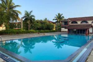 a large blue swimming pool in front of a house at The Greendoor Villa - Zalor, 500 mtrs to Beach in Orlim