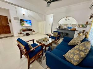 a living room with a blue couch and a table at The Greendoor Villa - Beach House , 400 mtr beach in Orlim