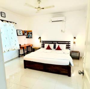 a bedroom with a bed with red pillows on it at The Greendoor Villa - Beach House , 400 mtr beach in Orlim +58 photos