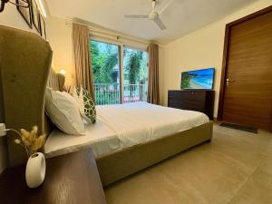 una camera da letto con un letto grande e una grande finestra di The Greendoor Villa - Veera Casa, pool, near beach ad Assagao
