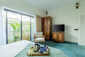 una camera con letto, TV e sedia di The Greendoor Villa - Bogen, Lux, Pvt Pool, beach ad Assagao