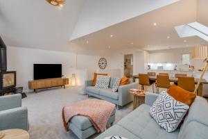 a living room with couches and a television and a kitchen at Schiehallion by Loch Tay in Chesthill