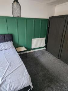 a bedroom with a bed and a green wall at Okwute,s House in Skelmersdale +5 photos