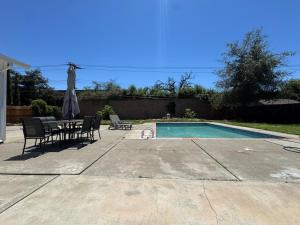 a pool with a table and chairs and an umbrella at Pool Remodeled 4 Bedroom Carmichael Home in Carmichael