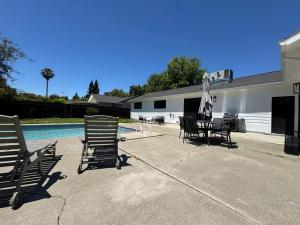 a patio with chairs and a table next to a pool at Pool Remodeled 4 Bedroom Carmichael Home in Carmichael