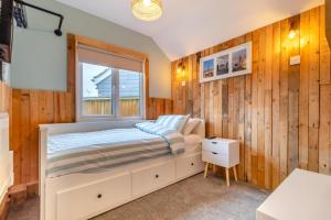 een slaapkamer met houten wanden en een bed met een raam bij The Shack in Lessingham