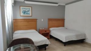 ein Zimmer mit zwei Betten und einem Glastisch in der Unterkunft Hotel los coloniales in Reynosa