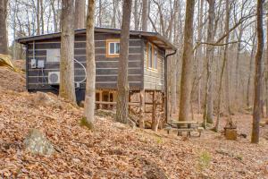 Una pequeña casa en el bosque con un banco en Creekside Retreat with Swimming Hole in Summerville, en Summerville