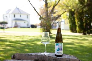 a bottle of wine and a glass on a stump at The Homestead Historic Charm & Big Backyard in Geneva
