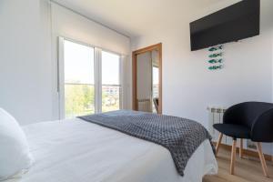 a white bedroom with a bed and a television at Baiona by Ladeira in Baiona