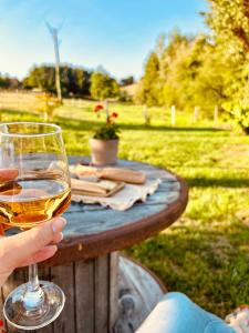 a person holding a glass of wine on a table at Chalet Zénaé - Chalet Cosy avec spa & Sauna in Vitrac +40 photos