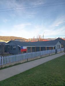 a train station with a white fence and a building at Mate Sur Hostal in Cochrane