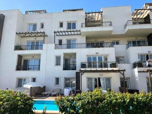 a large white building with a pool in front of it at Thalassa Beach Resort Apartment in Vavla