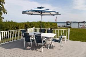 une table et des chaises avec un parasol sur une terrasse dans l'établissement Katies Cottage Lakefront Stay with Hot Tub and Kayaks, à Teall Beach