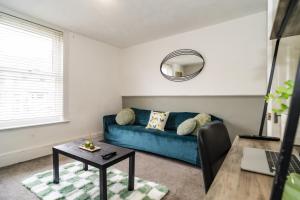 a living room with a blue couch and a table at Sage House (Town-Centre Flat) in Allington +26 photos