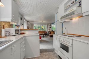 a kitchen with white appliances and a living room at C11259-Hemmet-Raevekrogen-82 in Højsand